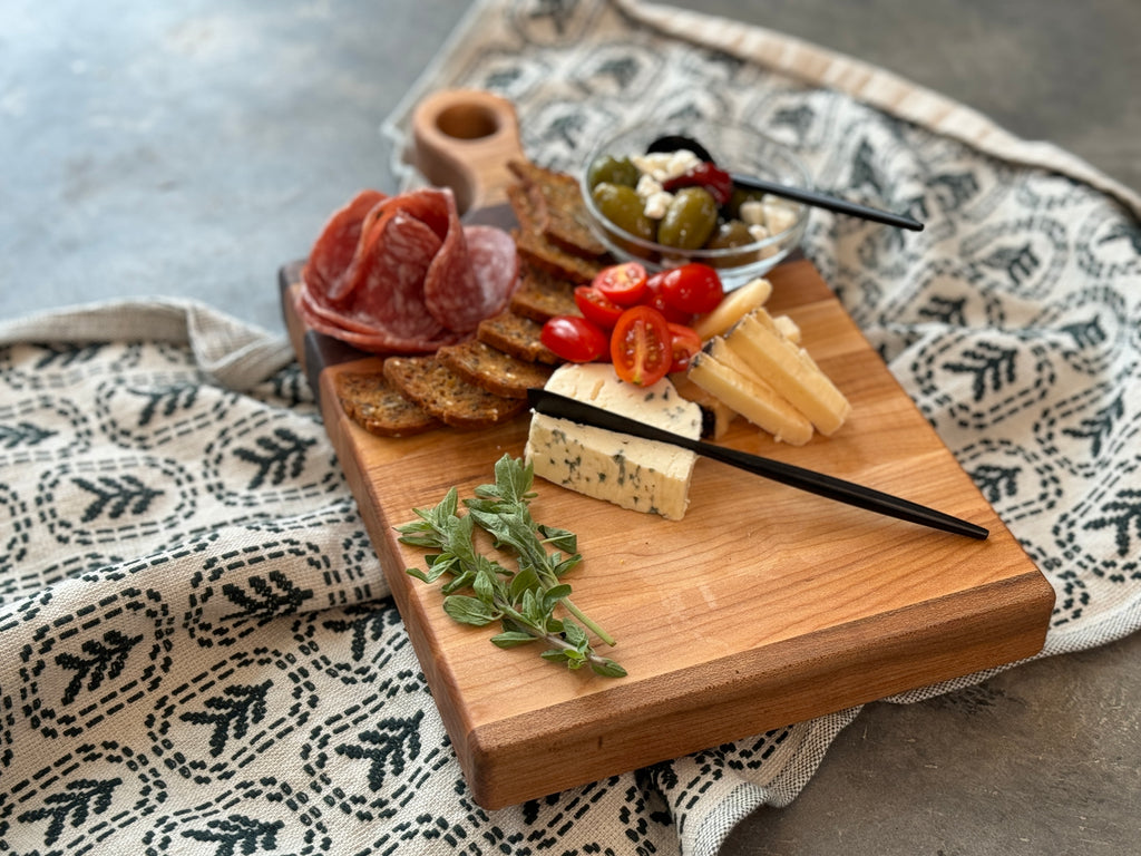 Small wooden charcuterie / cutting board featuring elegant walnut and maple stripes, garnished with Fresh salami, cheese, olives and fresh herbs. Perfect for hosting and gifting.