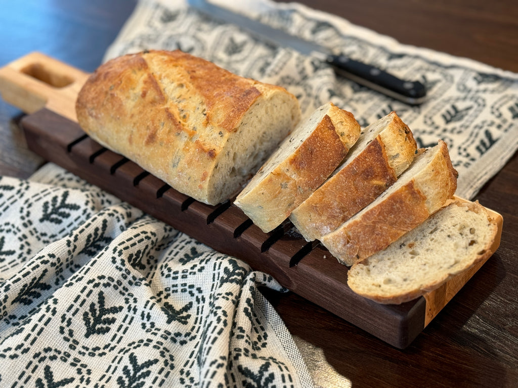 A maple and walnut bread board showcasing sliced bread