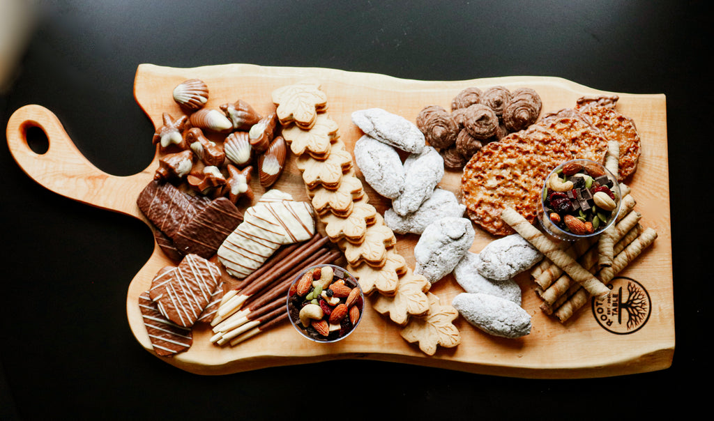 A handcrafted maple charcuterie board with a natural live-edge design showcased with desserts.