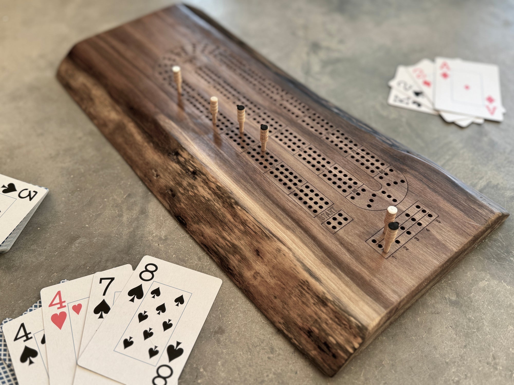 live edge walnut cribbage board with pegs and cards.