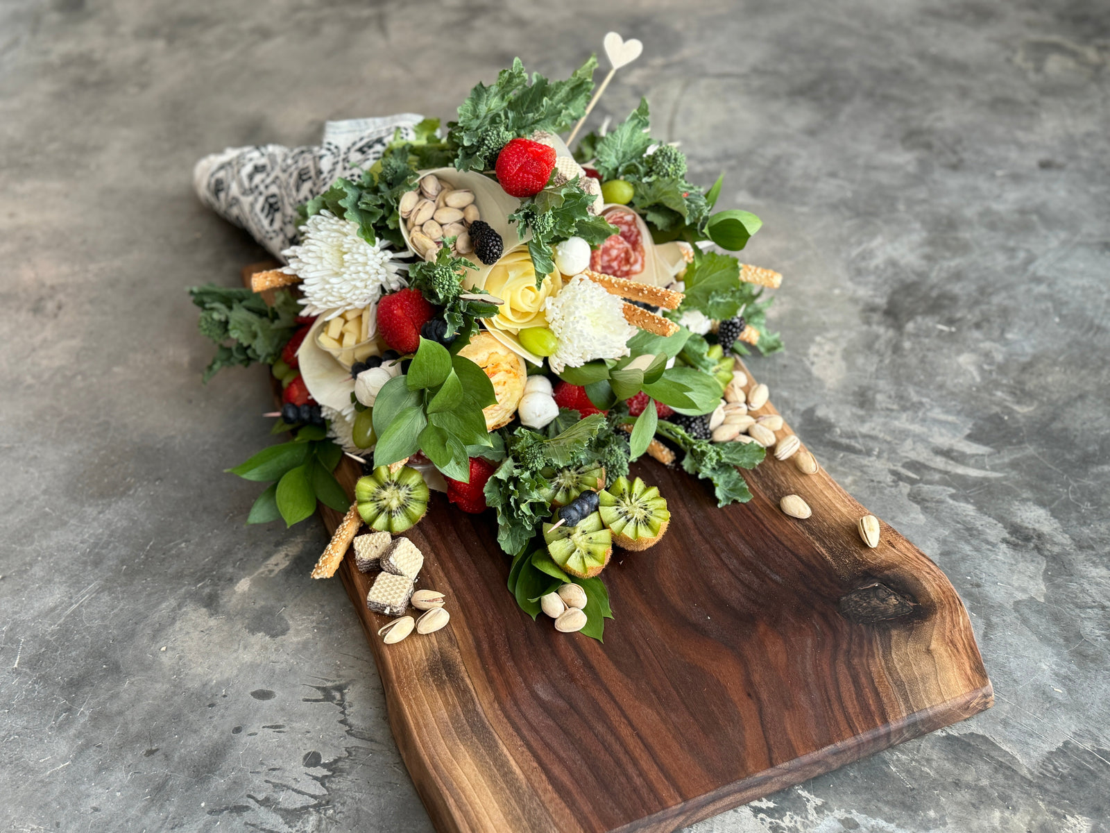 Spill over charcuterie bouquet on a walnut live edge board.