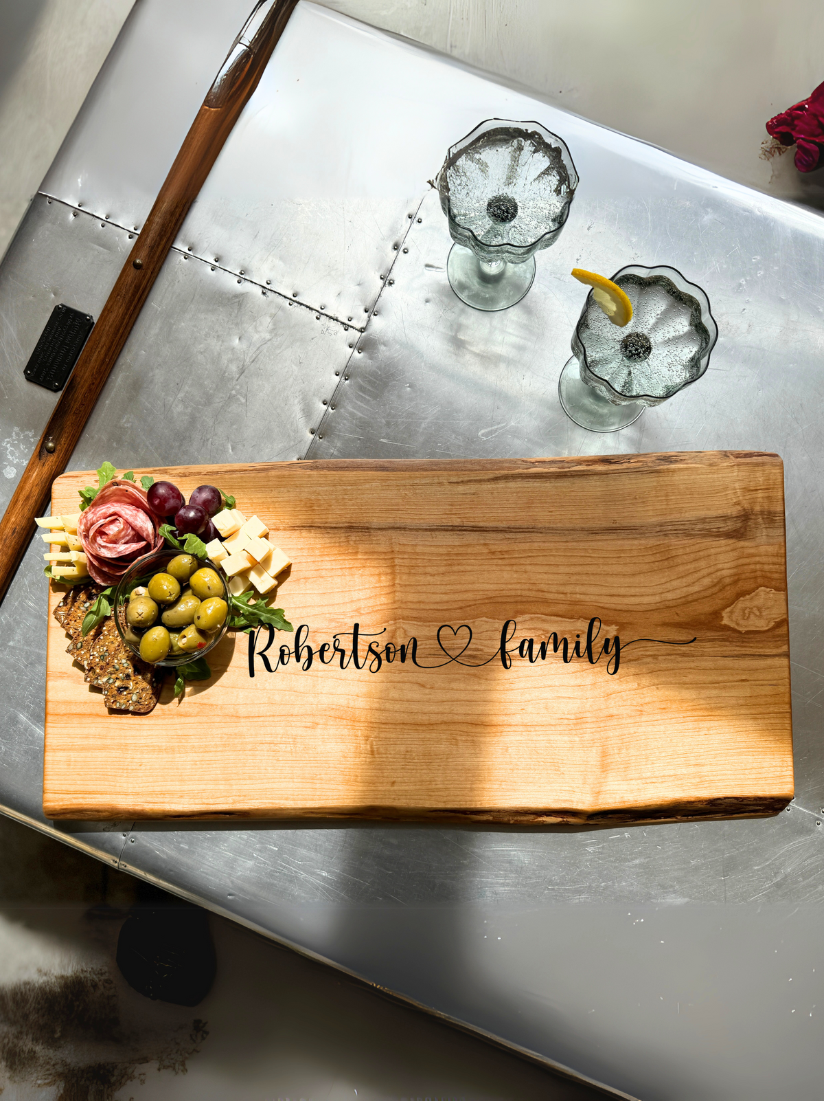 Live edge Maple charcuterie Board with personalization showcased on a metal coffee table.