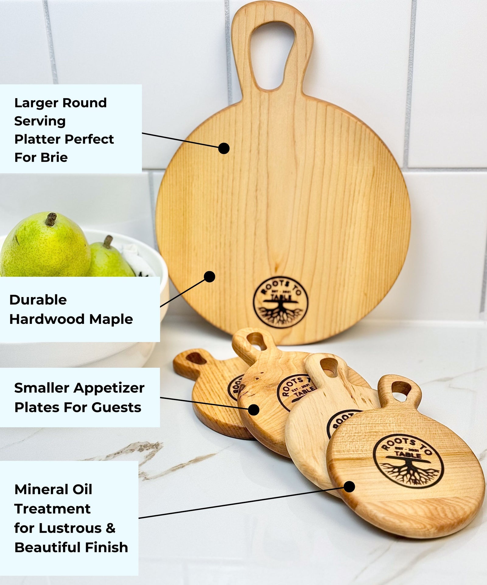 Round wooden cutting boards from Roots to Table, labeled with dimensions: Sprout board (12 inches tall, 9-inch diameter) and Seeds boards (6 inches tall, 4.5-inch diameter). Displayed on a white counter with pears in a bowl nearby.