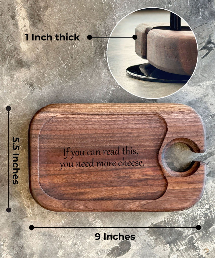 A rectangular dark walnut wine and cheese tray measuring 9 inches by 5.5 inches and 1 inch thick, featuring a wine glass holder and engraved text reading if you can read this, you need more cheese.