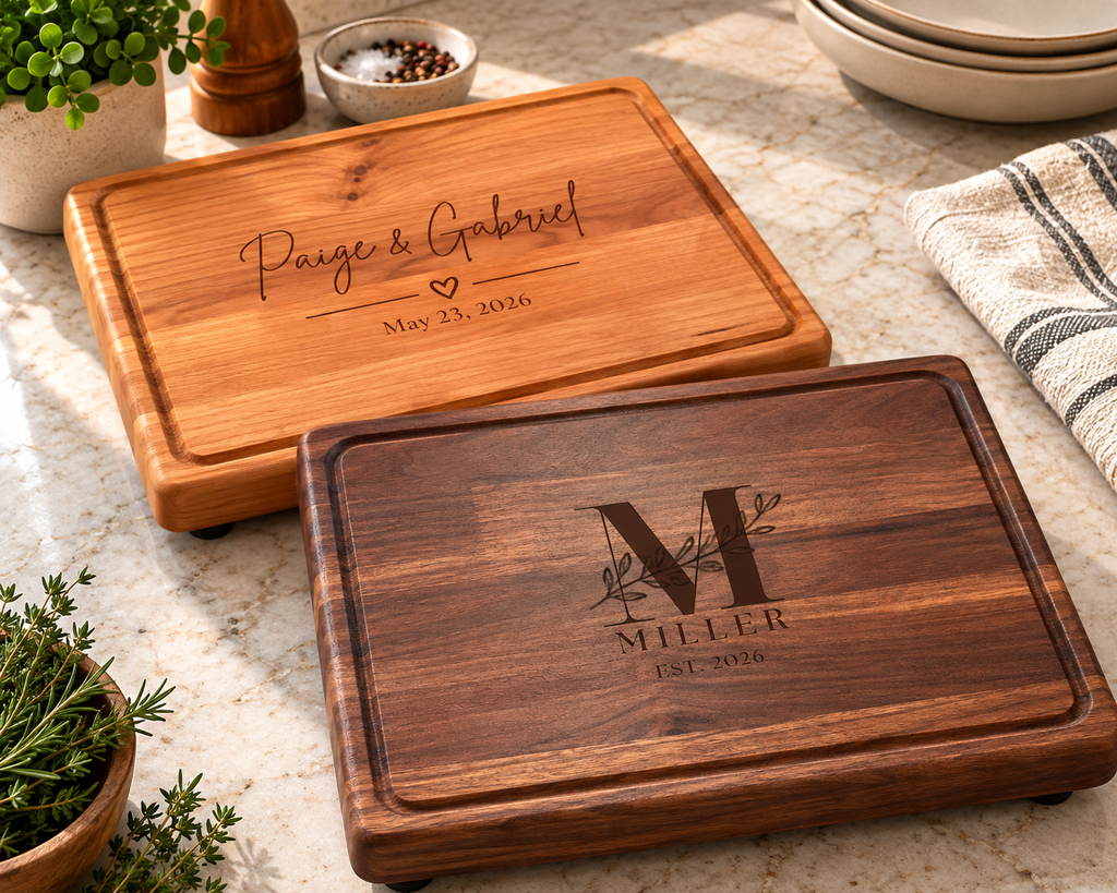 Two handcrafted personalized wooden cutting boards displayed together, showcasing different hardwood colours and custom engraving styles. Each board features beautiful natural wood grain, a routed juice groove and smooth rounded edges. Personalized cutting boards make thoughtful wedding, anniversary, housewarming and family gifts.