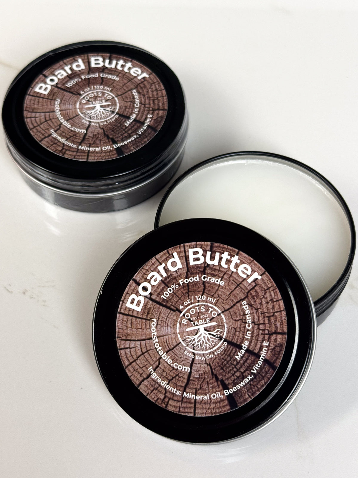 Open Tin of Roots to Table Board Butter, labeled as 100% food grade with ingredients including mineral oil, beeswax, and vitamin E. 