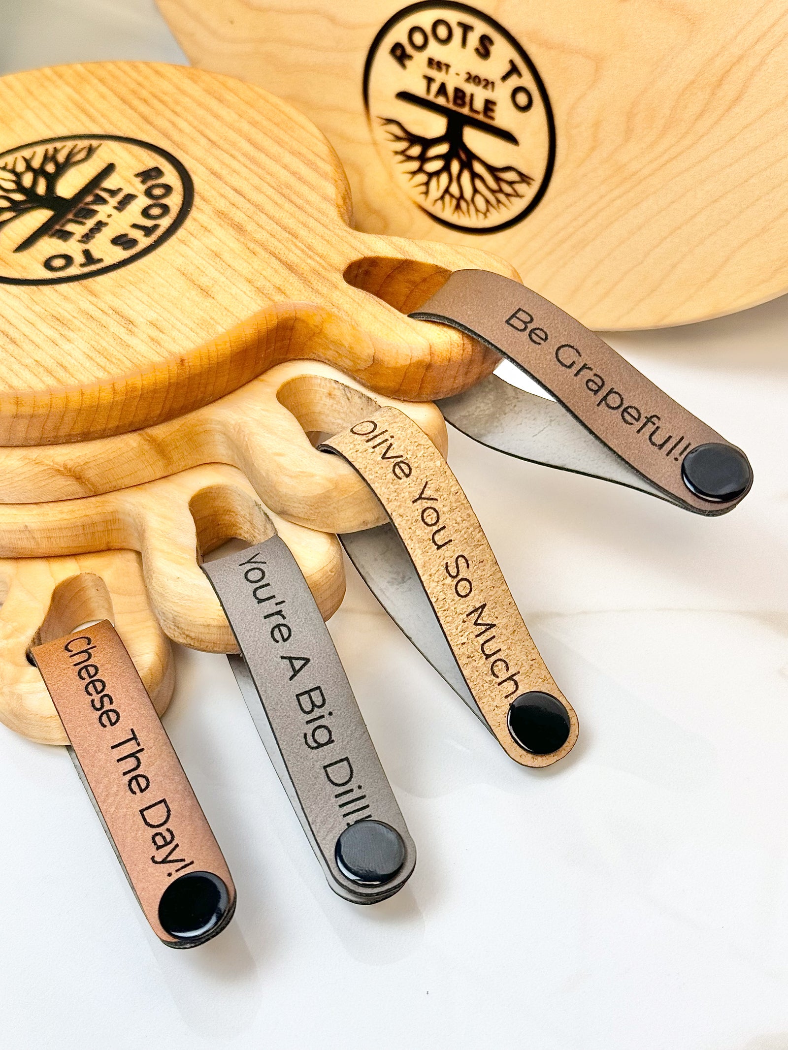 Maple wooden coaster single serve mini charcuterie board set with vegan leather straps engraved with puns: Be Grapeful!!, Olive You So Much, You;re A Big Dill!, and Cheese The Day! Coasters have a natural finish.