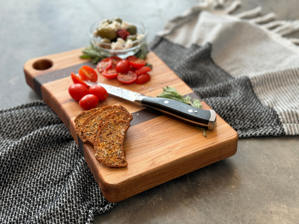 A close up side view of a walnut and maple cutting board with Edge Grain, handcrafted in Canada, and custom engraving options.