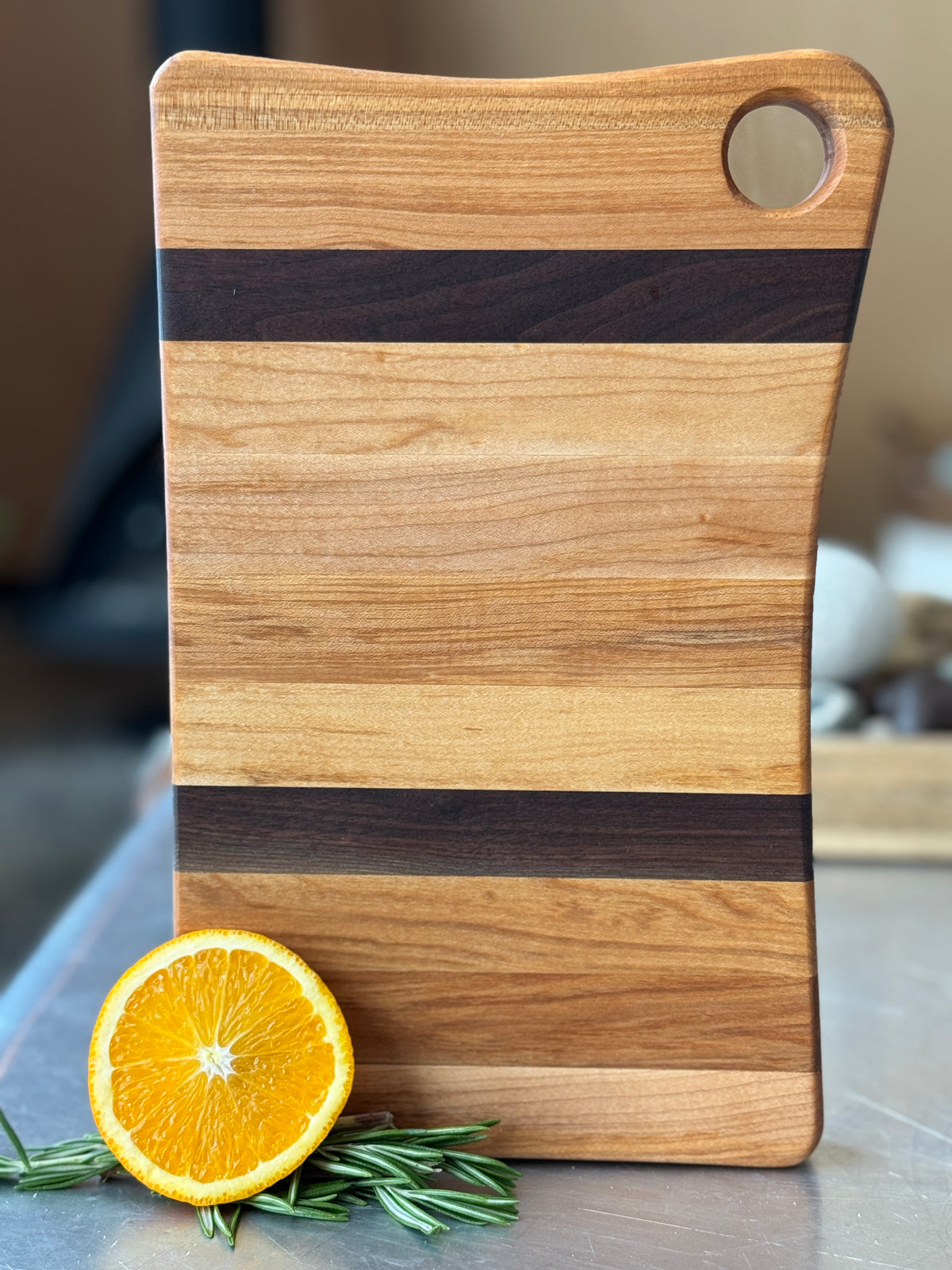 A small walnut and maple cutting board  reversible use, Edge Grain, handcrafted in Canada, and custom engraving options.