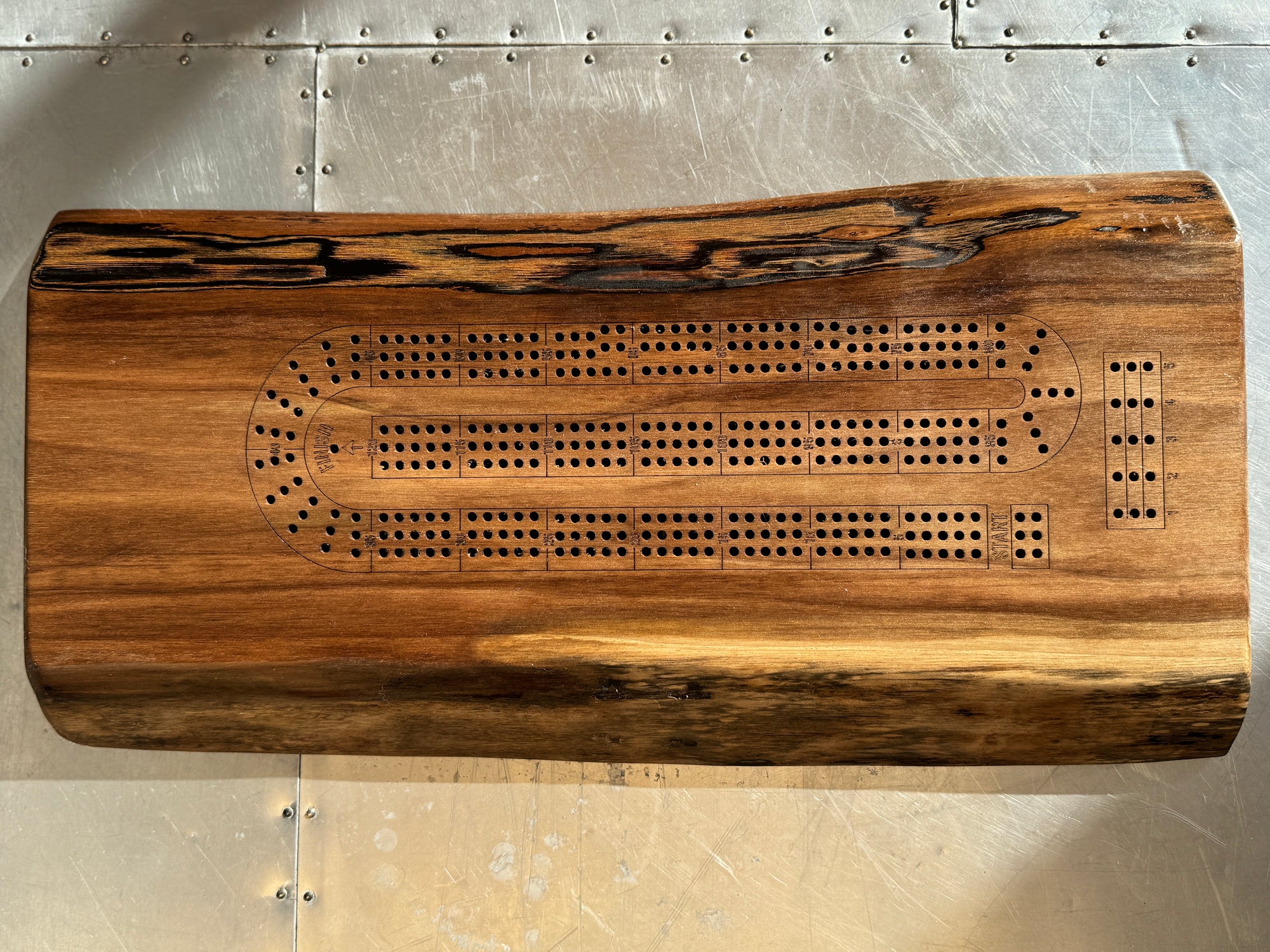 A handcrafted wooden walnut cribbage board measuring 16x6 inches, featuring a natural live-edge design. combining functionality and rustic elegance for family game nights.