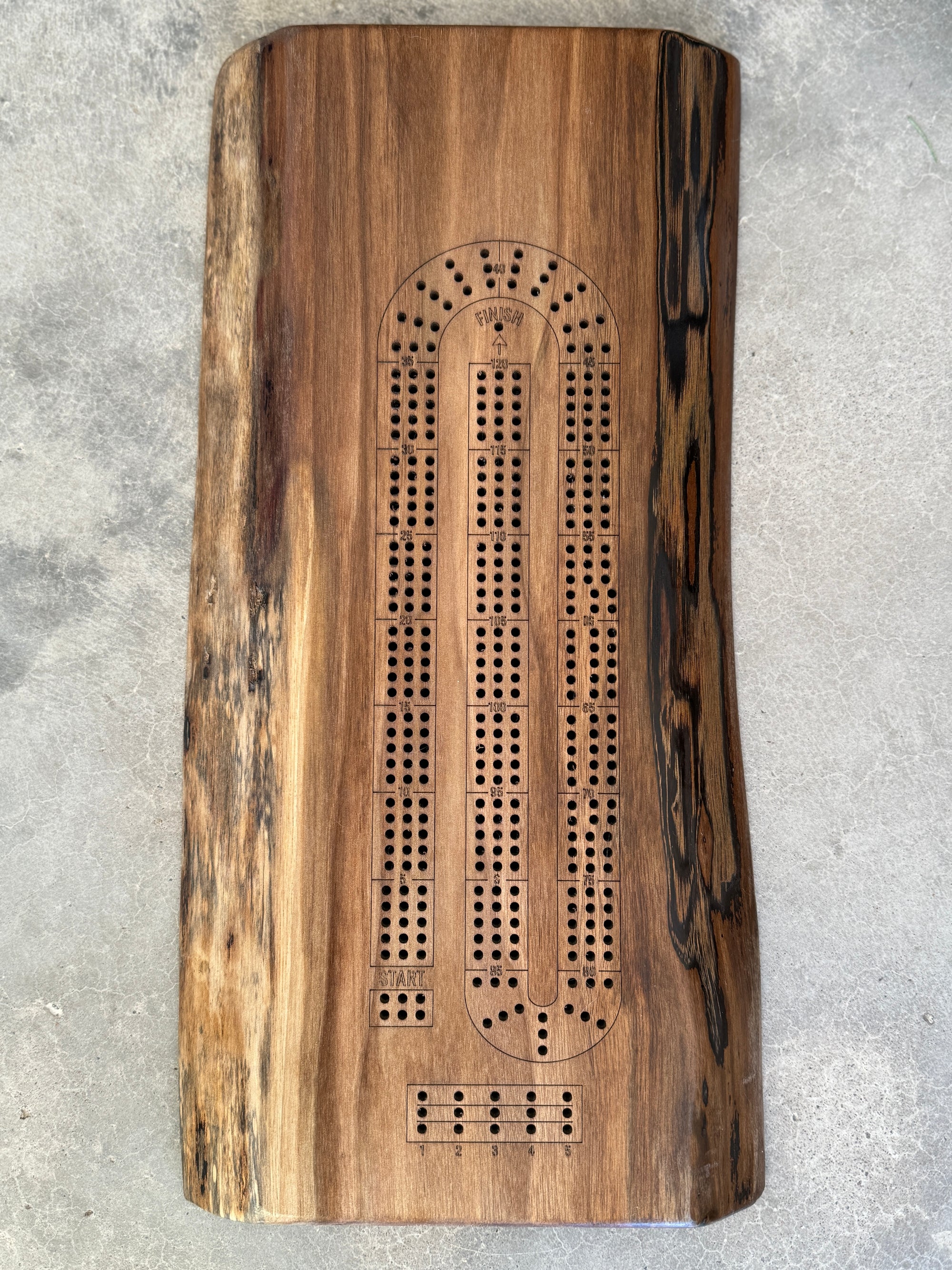 A handcrafted wooden walnut cribbage board measuring 16x6 inches, featuring a natural live-edge design. combining functionality and rustic elegance for family game nights.