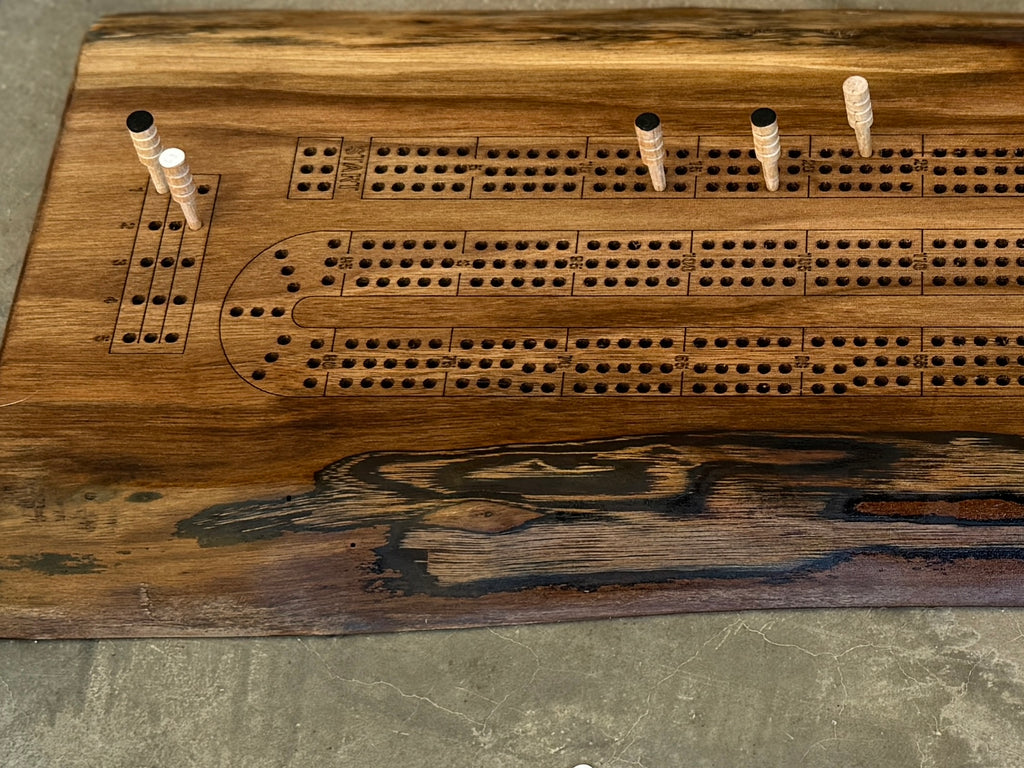 Side view of a live edge walnut crib board showing pegs that can be purchased as part of the set.