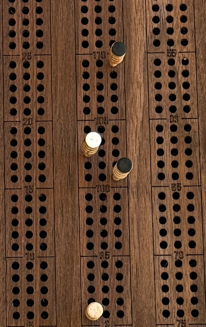 A close up of a walnut crib board showing wooden pegs that can be purchased as a set.