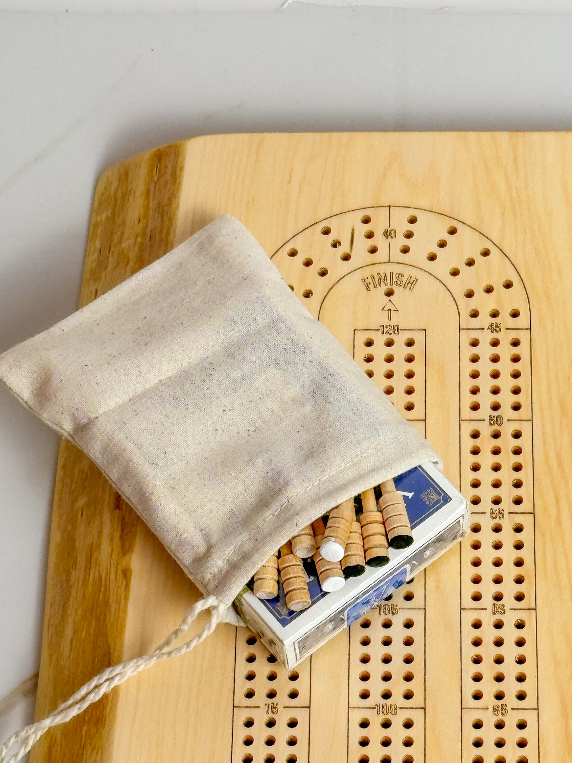 Image shows a finished live edge maple crib board with the full set. Set includes a small cloth sachet with a deck of cards and 9 wooden pegs.