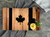 The Canadian flag striped maple and walnut cutting board with a laser-engraved, epoxy filled maple leaf in the center showcasing food items for size perspective