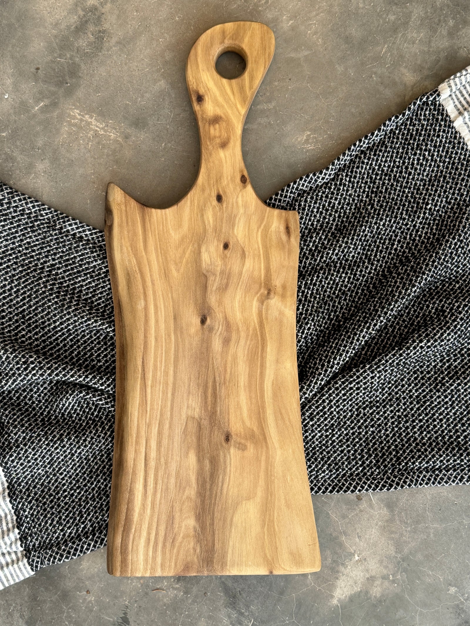 A handcrafted Sapwood Walnut cutting board featuring light, creamy wood tones with natural grain patterns. Personalized engraving reads "The Johnsons Est. 2024." Garnished with rosemary, cheese, salami, and berries for a decorative touch.