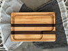 A handcrafted cutting board made from alternating strips of maple and walnut wood, featuring a juice groove for functionality and a smooth, polished finish.