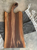 A Stunning 24 inch long black walnut live edge charcuterie board with handle showcases the multitude of colours and patterns walnut is known for.