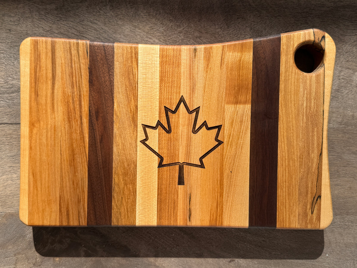 The Canadian flag maple and walnut cutting board with a laser-engraved, outline of maple leaf in the center.