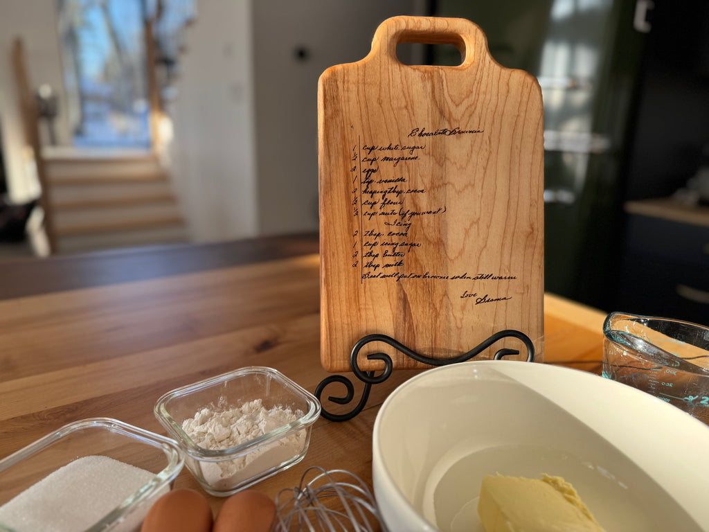 Maple cutting board with engraving resting in a stand with ingredients ready to make brownies