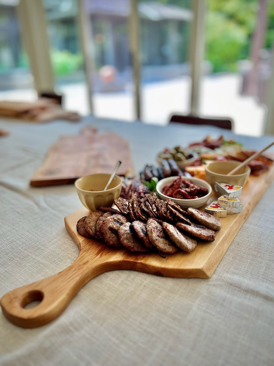A large live edge maple charcuterie board with a natural grain pattern, displayed charcuterie and dips.