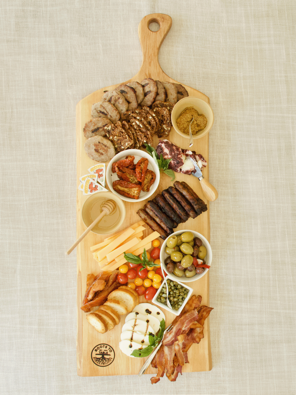 A large live edge maple charcuterie board with a natural grain pattern, displayed with charcuterie and dips.