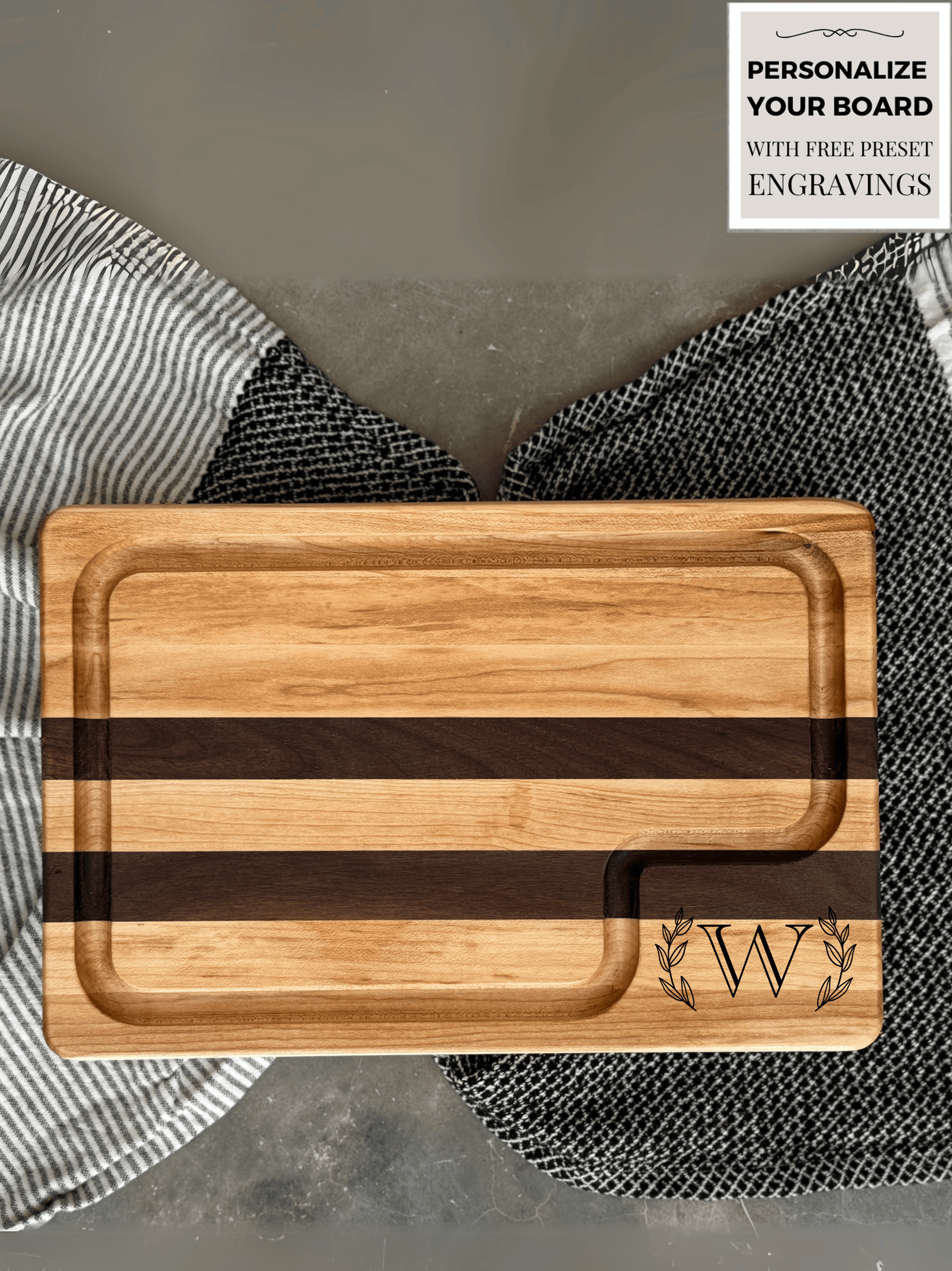 A handcrafted cutting board made from alternating strips of maple and walnut wood, featuring a juice groove for functionality and a smooth, polished finish. A customized letter W engraving surrounded by laurel leaves in the corner.