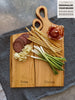 Two personalized wooden Live Edge charcuterie boards engraved with Anna and Marcus, nestle into each other creating one seamless board. The handles snug into one another like a friend resting resting their head on another&#39;s shoulders.