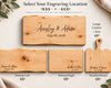 A graphic showing four engraved wooden serving boards arranged on a light neutral background with decorative leaves and fabric. The boards are shown in different shapes and sizes, including a large square charcuterie board, two smaller rectangular cuttings boards, and one handled board.