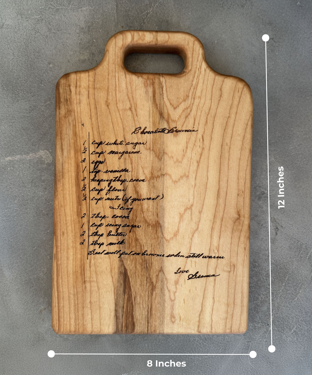 A handwritten brownie recipe is engraved onto a maple cutting board showing 8 inch by 12 inch dimensions