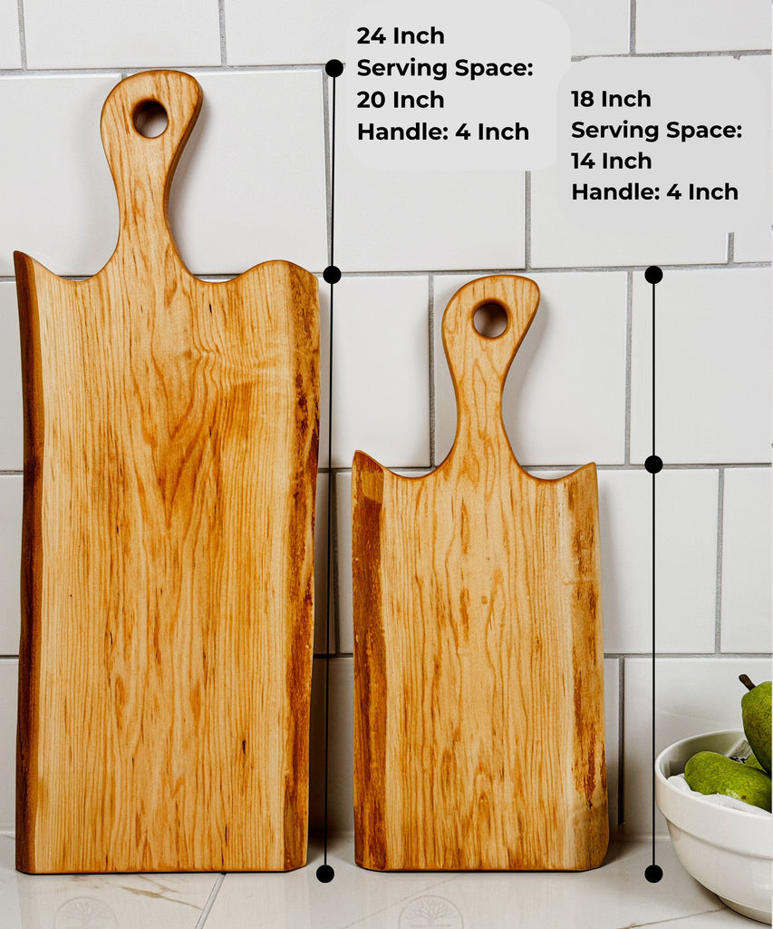 Two handcrafted Live Edge maple serving boards displayed upright, featuring natural wood grain and dimensions labeled. The larger charcuterie board is 24 inches with a 20-inch serving space, and the smaller is 18 inches with a 14-inch serving space.