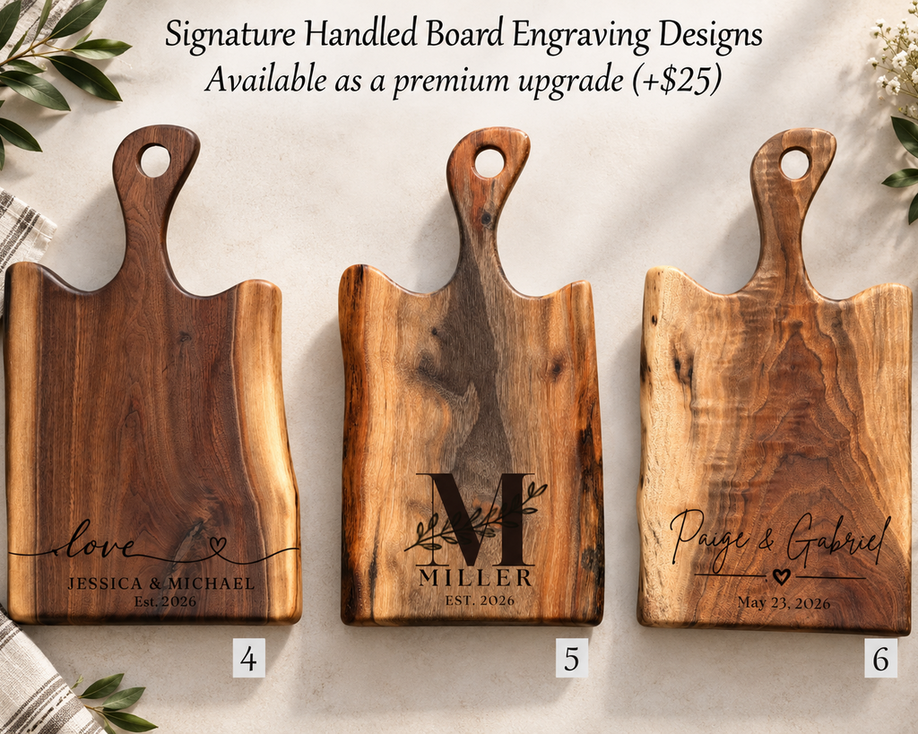 Three wooden handled cutting boards with different engraved designs are displayed on a light textured background with decorative greenery and a napkin. Text at the top reads 'Signature Handled Board Engraving Designs Available as a premium upgrade (+$25)'.