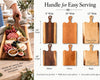Six wooden serving boards with handles in different widths and wood tones are shown, with one board being carried by a person on the left. The right side includes a labeled diagram comparing handle widths (8" wide, 10" wide, 12" wide) and heights (24" length, 18" length), plus wood type options: Walnut, Cherry, and Maple.