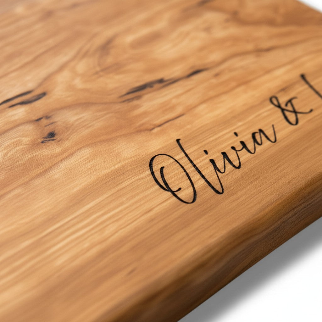 Wooden cutting board with engraved text on a light wood background. Close-up of engraved cherry live edge charcuterie board with custom name