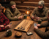 Four men sitting around a rustic wooden table in a cozy cabin setting, playing a cribbage game. the crib board is live edge maple wood.
