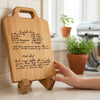 Personalized cutting board with wooden stand, engraved with hand written recipe and sits as home decor on kitchen counter