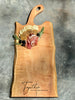 24-inch maple live edge charcuterie board with a curved handle, beautifully arranged with cheeses, meats, and fruit, featuring an engraving that reads “Together is my favourite place to be.”
