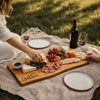 Person enjoying a Cherry live edge charcuterie board used for outdoor picnic with wine and snacks