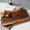 Natural wooden charcuterie board with personalized engraving on a marble surface with wine and flowers celebrating anniversary