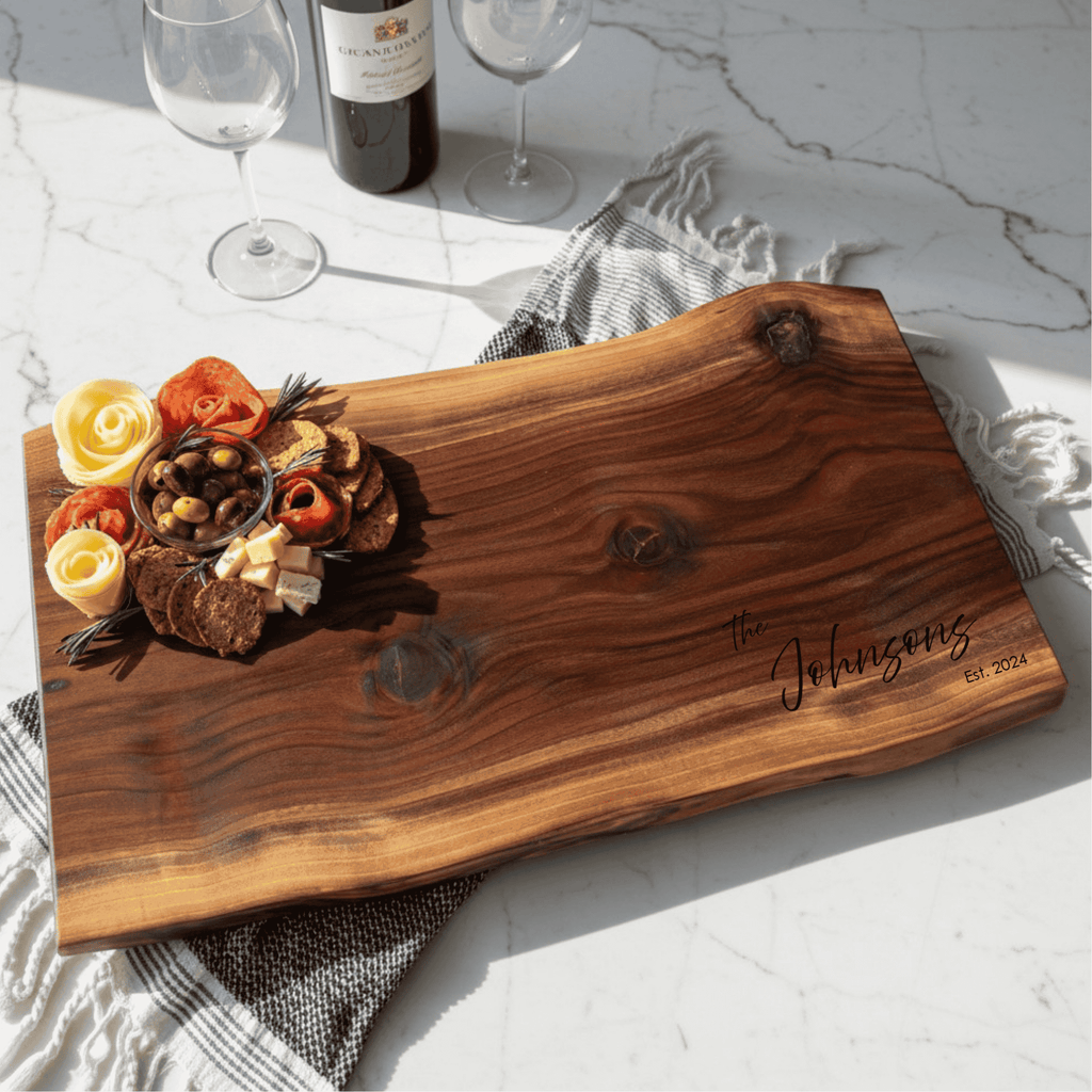 Natural wooden charcuterie board with personalized engraving on a marble surface with wine and flowers celebrating anniversary