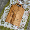 A handwritten brownie recipe is engraved onto a maple cutting board, displayed on a  vintage tea towel.