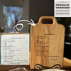 A handwritten brownie recipe is engraved onto a maple cutting board, displayed on a stand. The original recipe note is shown in the corner with a personalize your board badge with free preset engravings
