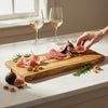 maple cutting board with figs, prosciutto, and salami on a marble surface with two glasses of white wine ready for couple celebrating anniversary