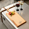 Wooden cutting board with engraving of the family name set with wine and charcuterie for date night.