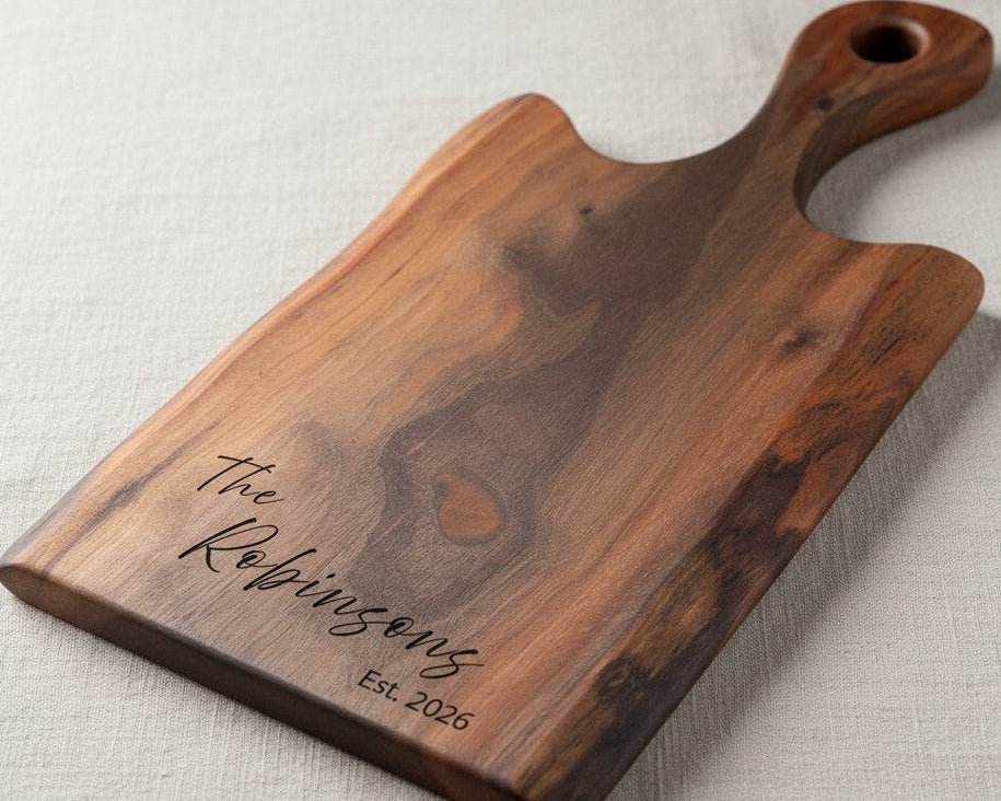 Wooden cutting board with engraved text 'The Robinsongs Est. 2026' on a beige background