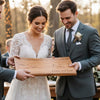 Wedding couple holding a wooden cutting board with engraved personalization.