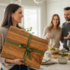Woman gifting a wooden cutting board with a green ribbon in a kitchen setting to a new homeowners as a housewarming gift.